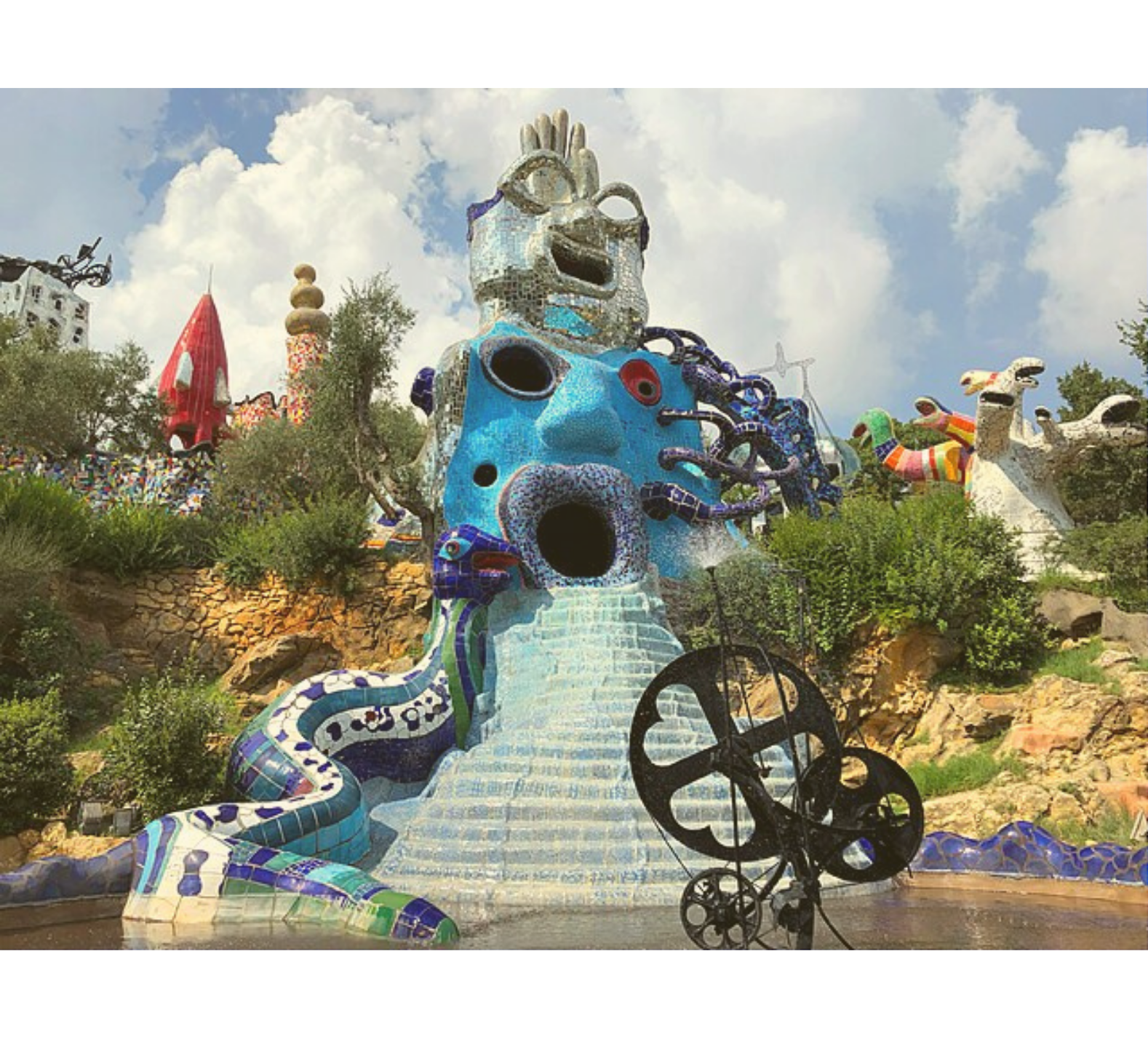 Giant blue sculpture of a face with an open mouth and stairway leading to water in Niki de Saint Phalle’s Tarot Garden.